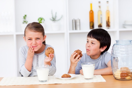 Happy Siblings eating cookies and drinking milk Happy Siblings eating cookies and drinking milk