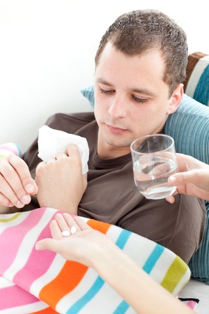 Sick man taking medicine on the sofa Sick man taking medicine on the sofa