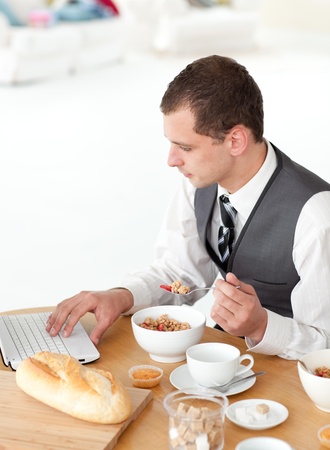 Young businessman using a laptop while having breakfast の写真素材