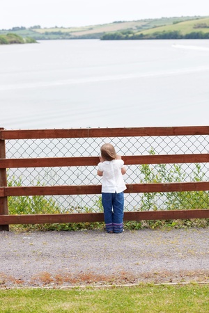 Little child standing in front of a fenceの写真素材