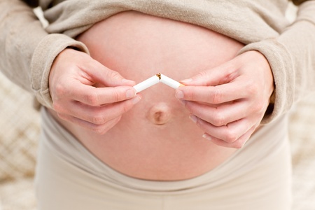 Close up of an attentive pregnant woman breaking a cigarette の写真素材