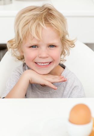 Cute little boy sitting at a table to eat a boiled eggの写真素材