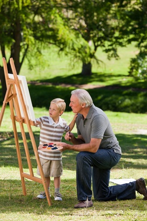 Grandfather and his grandson painting in the gardenの写真素材