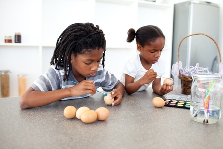 Concentrated Afro-american siblings painting eggs の写真素材