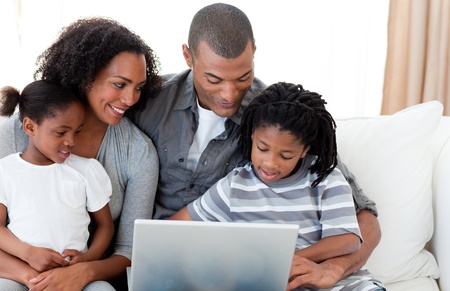 Afro-American family using a laptop on the sofa