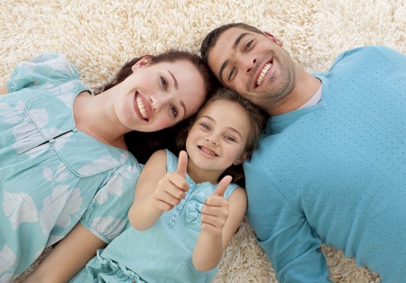 Parents and little girl on floor with thumbs upの写真素材