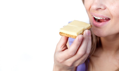 Close-up of a woman eating a cracker with cheese の写真素材