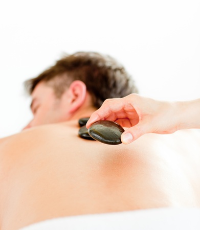 Close-up of a positive young man having a back massage with hot stoneの写真素材
