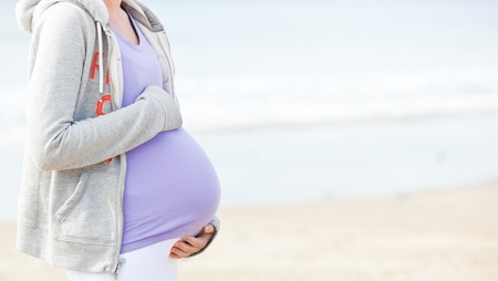 Pregnant young woman walking on the beach の写真素材