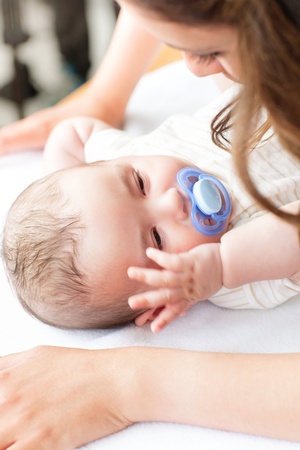 Close-up of a baby lying on a changing table while his mother is changing his nappy