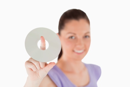 Attractive woman holding a CD while standing against a white background