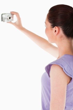 Charming woman using a camera while standing against a white backgroundの写真素材