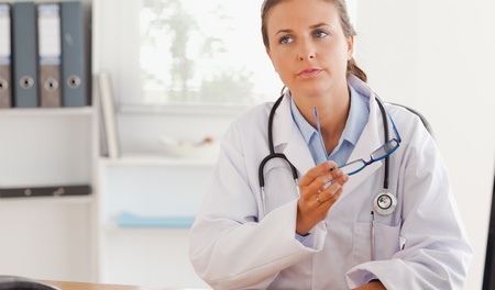 Female doctor posing with glasses in her officeの写真素材