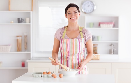 Short-haired brunette woman preparing a cake in a kitchen