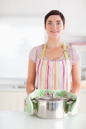 Smiling woman holding a pot in a kitchenの写真素材