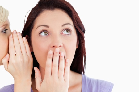 Close up of a cute women being told a secret in a studio