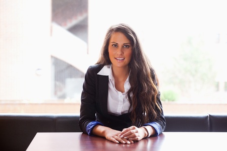 Young woman sitting at a table while looking at the cameraの写真素材