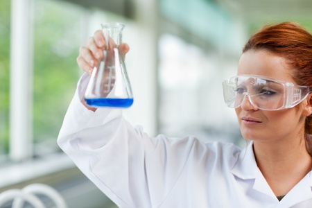 Science student looking at an Erlenmeyr flask in a laboratoryの写真素材