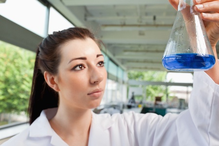 Brunette looking at a blue liquide in a laboratoryの写真素材
