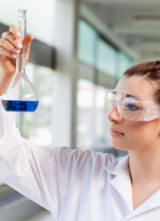 Portrait of a young science student looking at a blue liquid in a laboratoryの写真素材