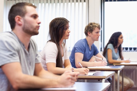 Studious young adults listening a lecturer in a classroomの写真素材