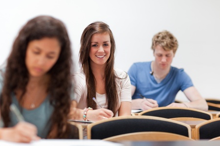 Smiling young students sitting on a chair in an amphitheaterの写真素材