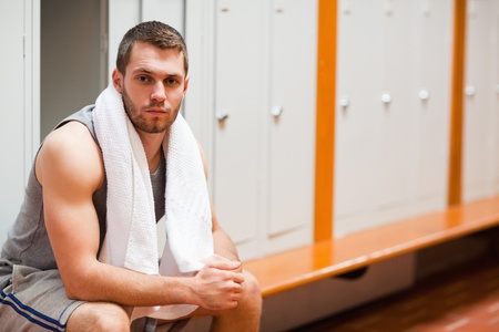 Handsome sports student sitting on a bench with a towelの写真素材