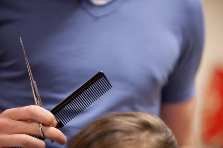 Close up of scissors and a comb hold by a handの写真素材