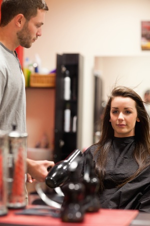 Portrait of a male hairdresser blowing hair of a customerの写真素材