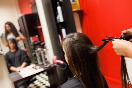 Cute woman having her hair straightened by an hairdresserの写真素材