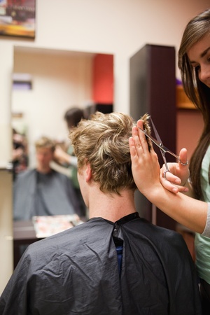 Portrait of a blond-haired man having a haircut with scissorsの写真素材