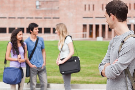 Student looking at his classmates talking outside a buildingの写真素材