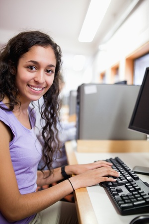 Portrait of a cute smiling student with a computer in an IT roomの写真素材