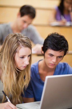 Portrait of students working with a laptop in an amphitheaterの写真素材
