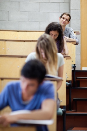 Portrait of young students writing in an amphitheater with the camera focus on the backgroundの写真素材