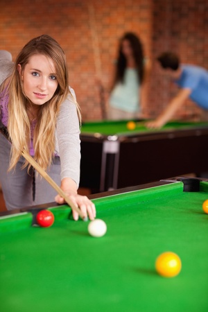 Portrait of a young woman playing snooker in a student homeの写真素材