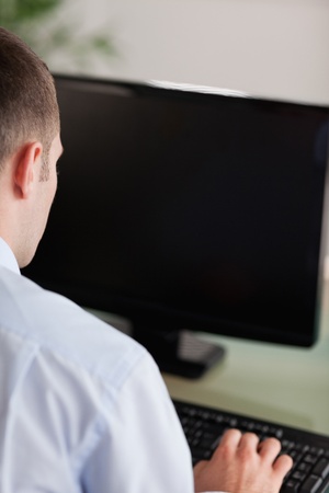 Close up of young businessmans back working on his computerの写真素材