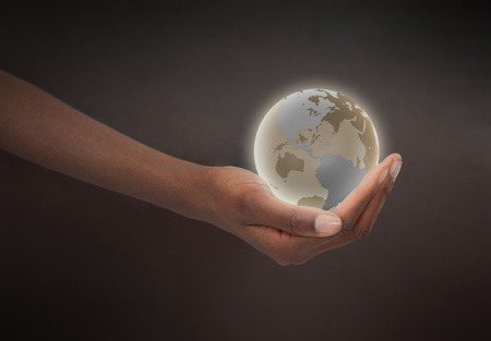 Feminine hand holding a glowing planet globe against a dark backgroundの写真素材