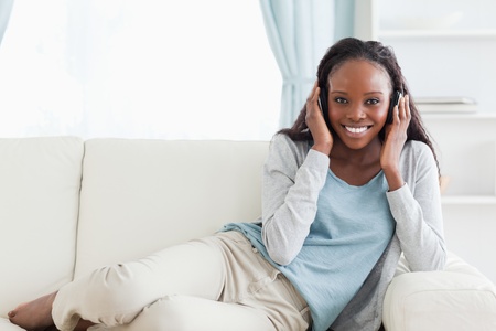 Smiling woman relaxing on sofa with headphones onの写真素材