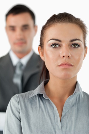 Close up of serious looking businesswoman with colleague behind her against a white backgroundの写真素材