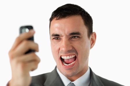 Close up of businessman upset about text message against a white backgroundの写真素材