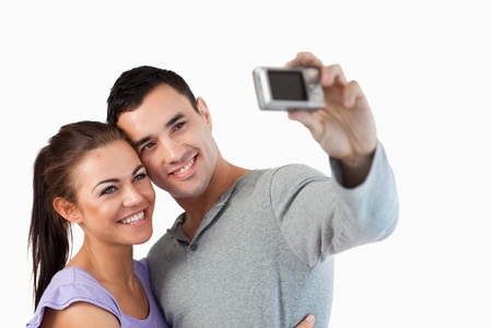 Young couple taking a picture of themselves against a white backgroundの写真素材
