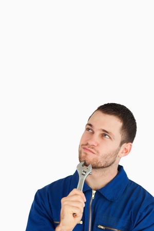 Young mechanic in boiler suit in thoughts against a white backgroundの写真素材