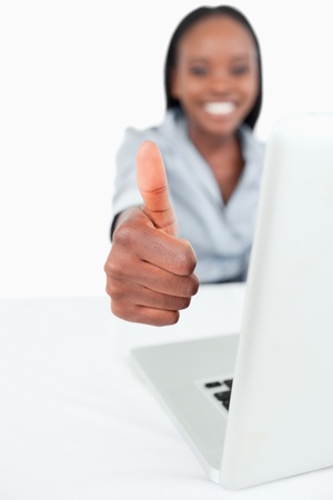 Portrait of a businesswoman using a laptop with the thumb up against a white backgroundの写真素材