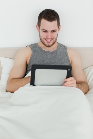 Portrait of a smiling man using a tablet computer in his bedroomの写真素材