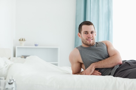 Man posing on his bed while looking at the cameraの写真素材