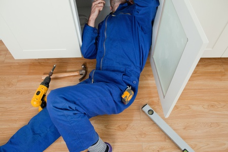 Repair man fixing something while lying on the floor