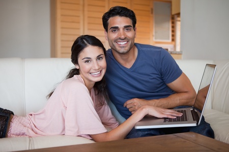 Lovely young couple using a notebook in their living roomの写真素材