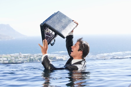 Businessman looking in his briefcase in a swimming poolの写真素材