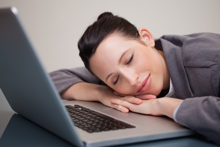 Young businesswoman taking a small nap on her laptopの写真素材